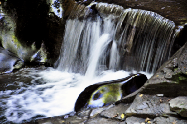 a small waterfall and a big rock